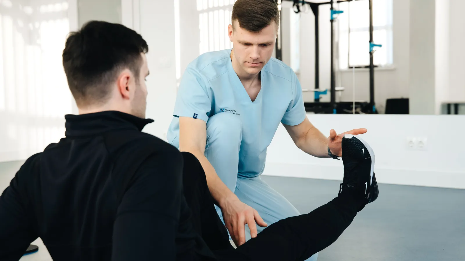 A physiotherapist examining a patient's knee with the leg held straight